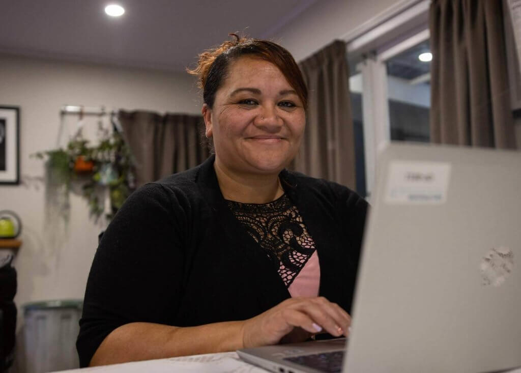 Debt help client, Rose, smiles at her computer that she bought with her savings