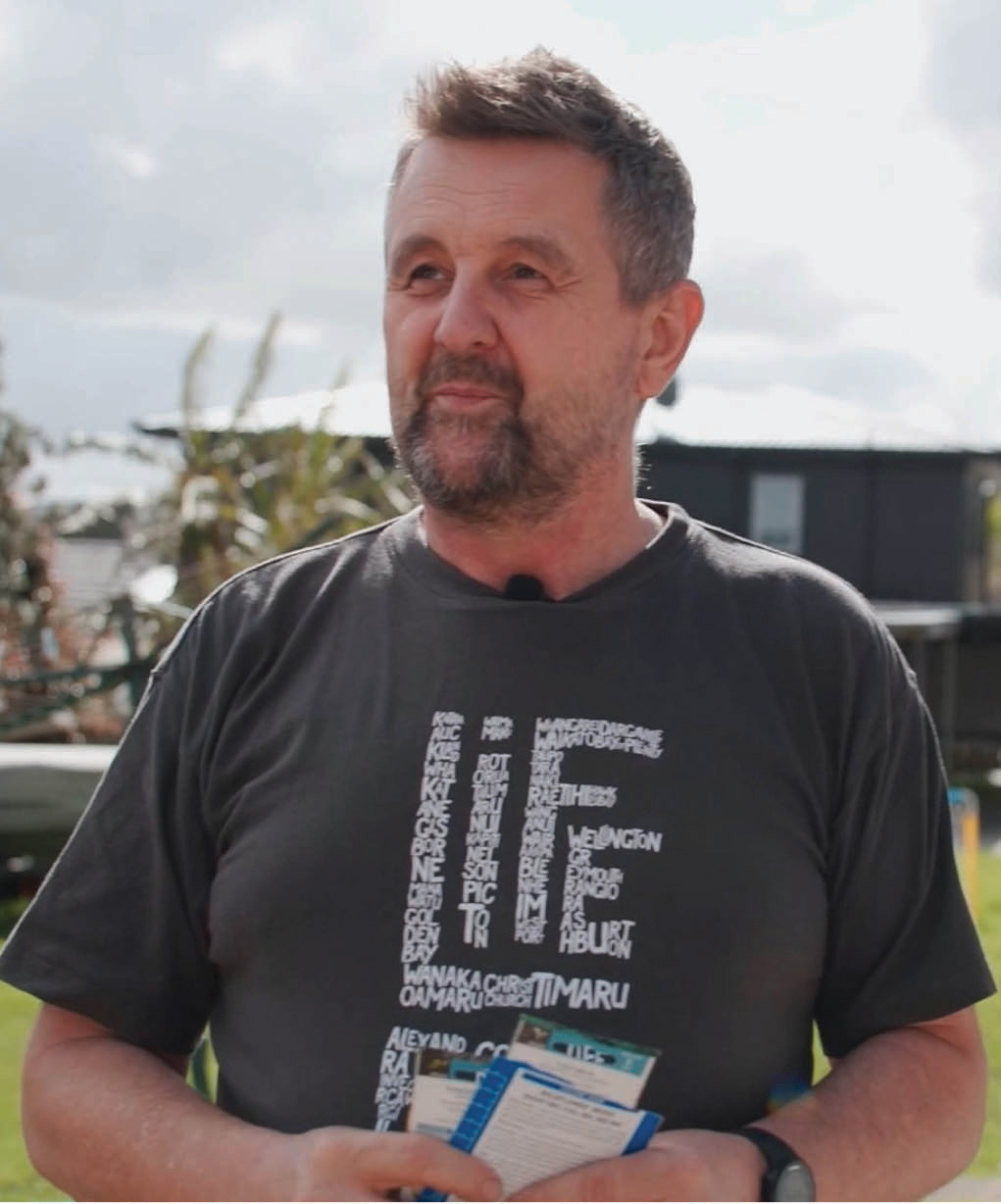 Lee standing outside in his garden holding seed packets